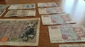Vecchie banconote italiane in lire disposte su un tavolo di legno