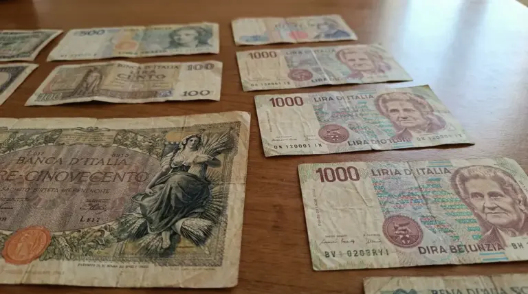 Vecchie banconote italiane in lire disposte su un tavolo di legno