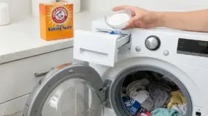 Una mano versa bicarbonato nel cassetto di una lavatrice con panni all'interno