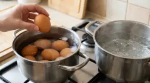 Uova immerse in acqua fredda accanto a una pentola con acqua che bolle su un fornello