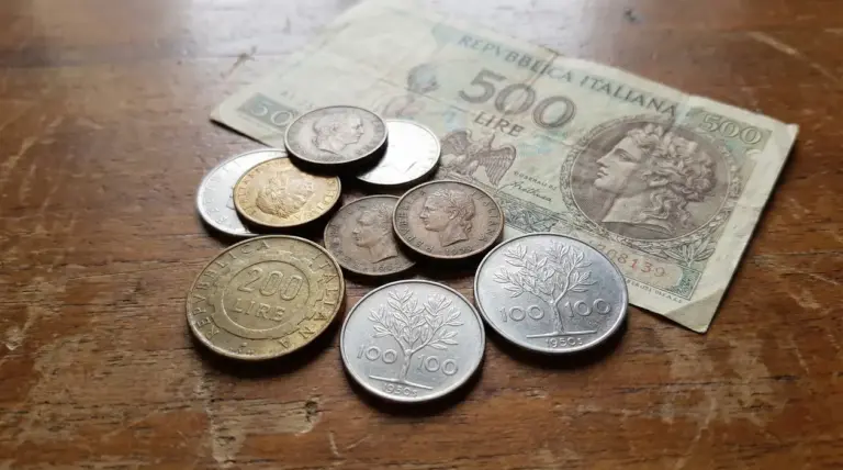 Vecchie monete e una banconota da 500 lire italiane su un tavolo in legno